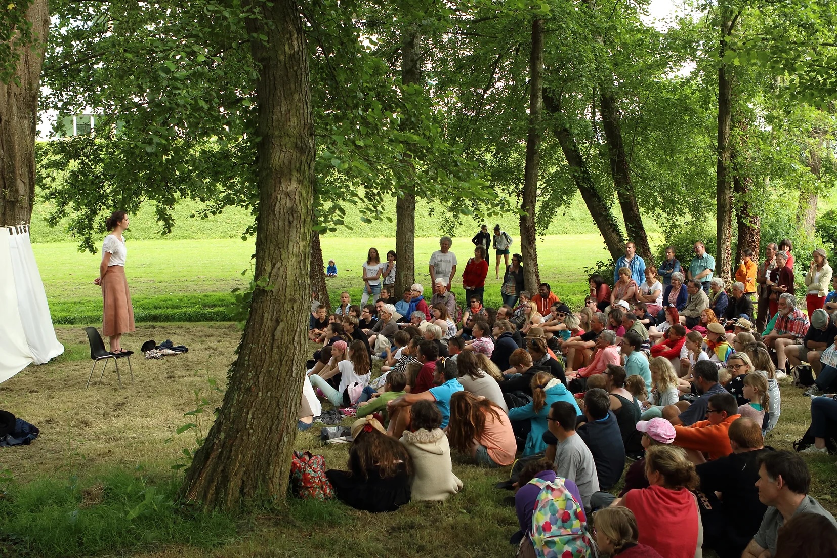 Audience sat in wooded area watching performance