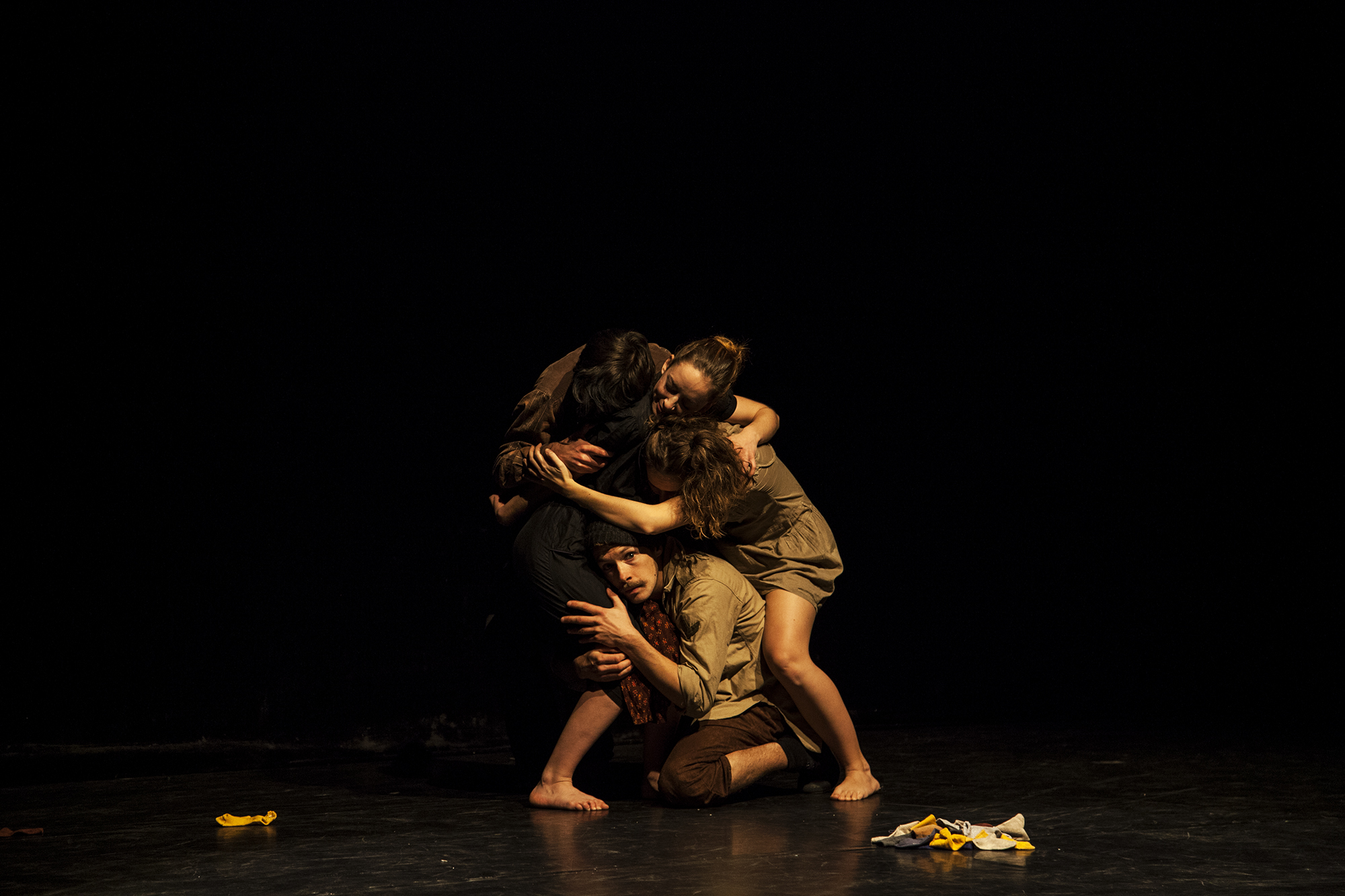 Performer cowering under other performers huddled together