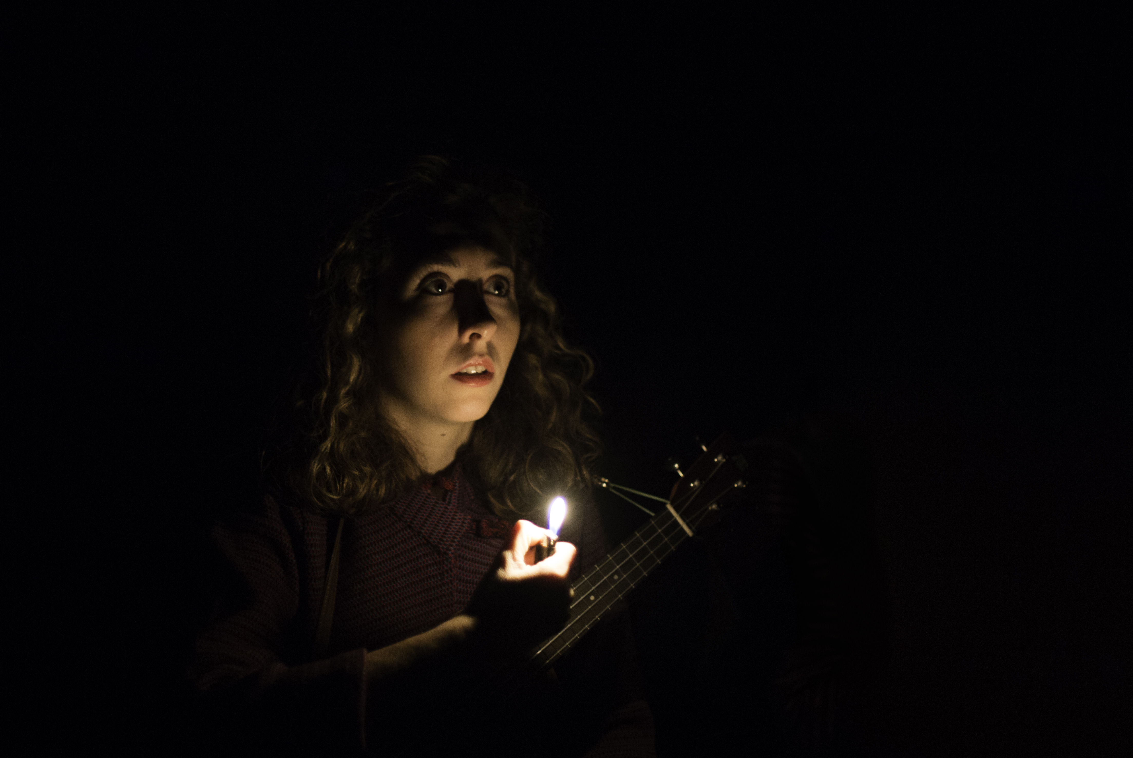 Giorgia holding ukulele in light of flame from lighter