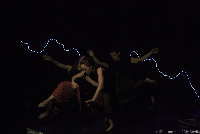 Performers performing physical theatre with lighting strike in background