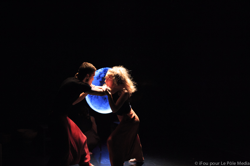 Giorgia and performer entangled in fight with moon in background