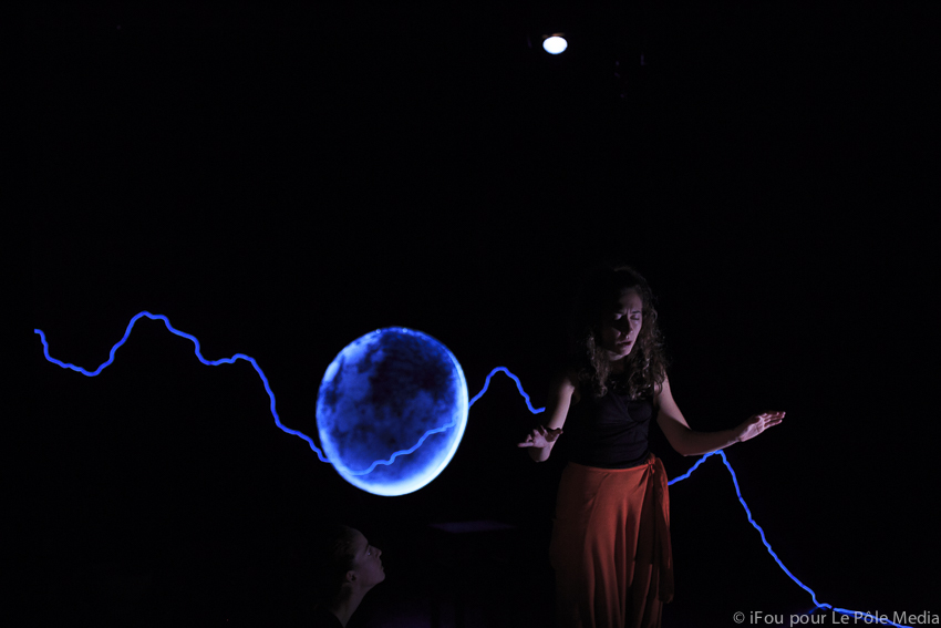 Giorgia concentrating, eyes closed and arms outreached. Moon and lighting in background