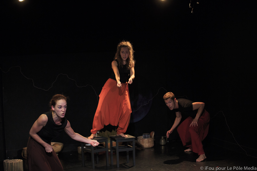 Giorgia story telling on chairs, performers doing physical theatre below her