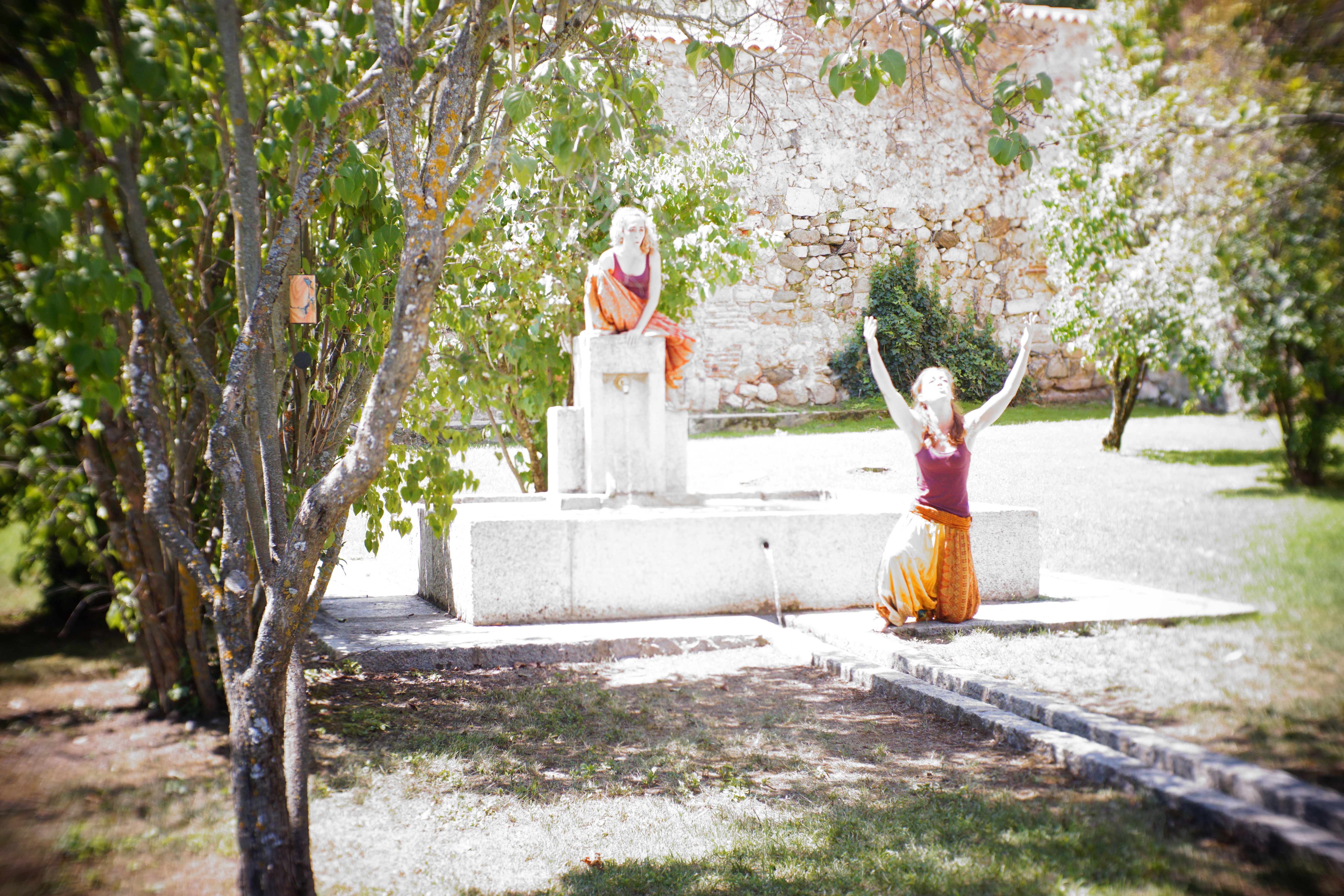 Giorgia sat on top of water fountain, perfomer on knees, arms up to the sky